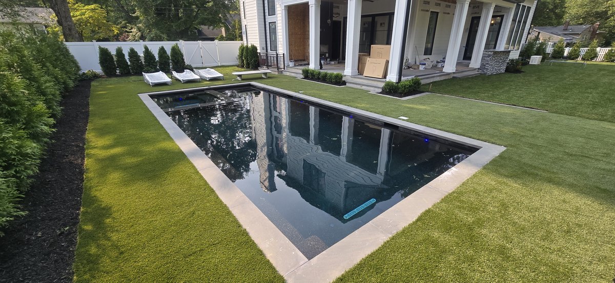 Modern in-ground pool with dark finish inspected by Aquatic Pool Inspections for home buyers